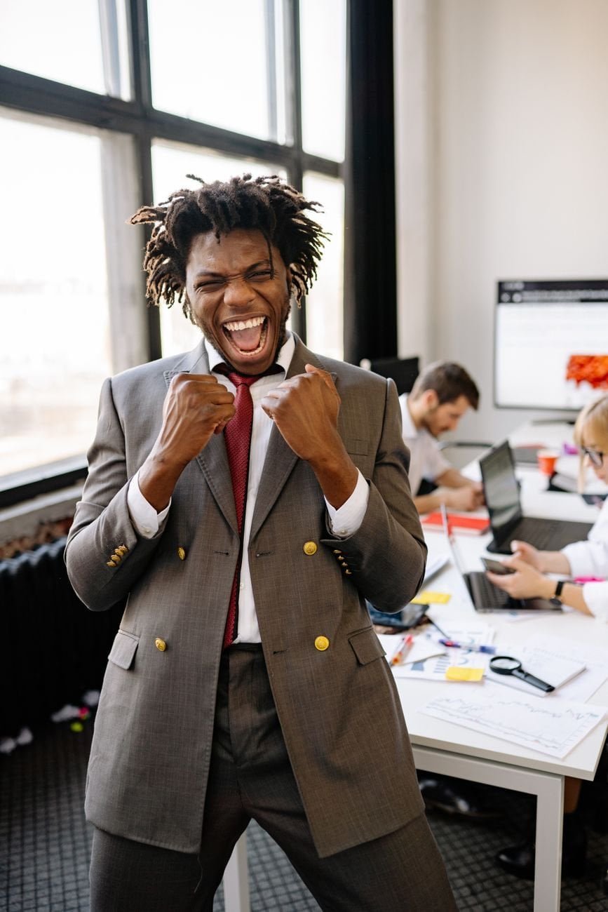 Excited African American businessman celebrating success with joy in an office setting.