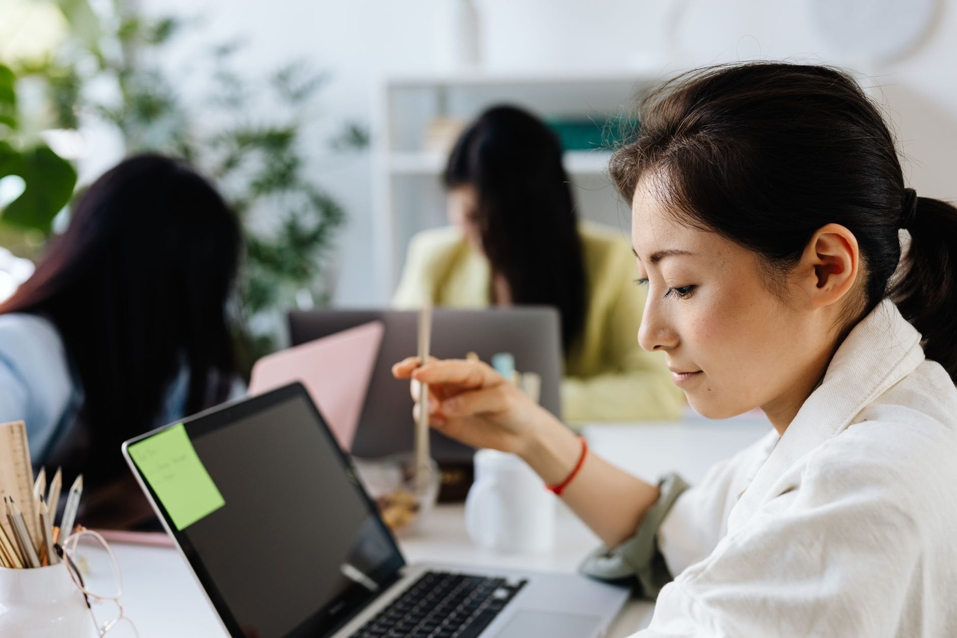 A focused woman working at her laptop in a bright, modern office setting.